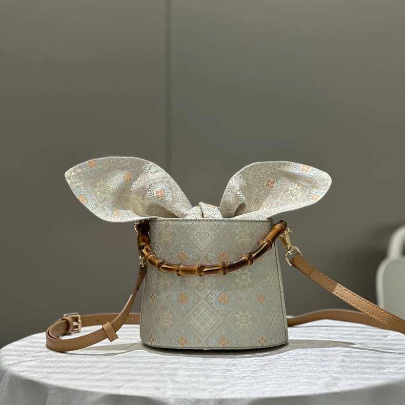 Handmade Zhuang Brocade Bucket Bag with Bamboo Handle | Artisan Crafted Ethnic Crossbody Bag with Bunny-Ear Brocade Flap