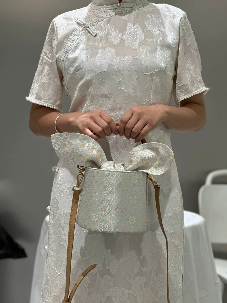 Handmade Zhuang Brocade Bucket Bag with Bamboo Handle | Artisan Crafted Ethnic Crossbody Bag with Bunny-Ear Brocade Flap